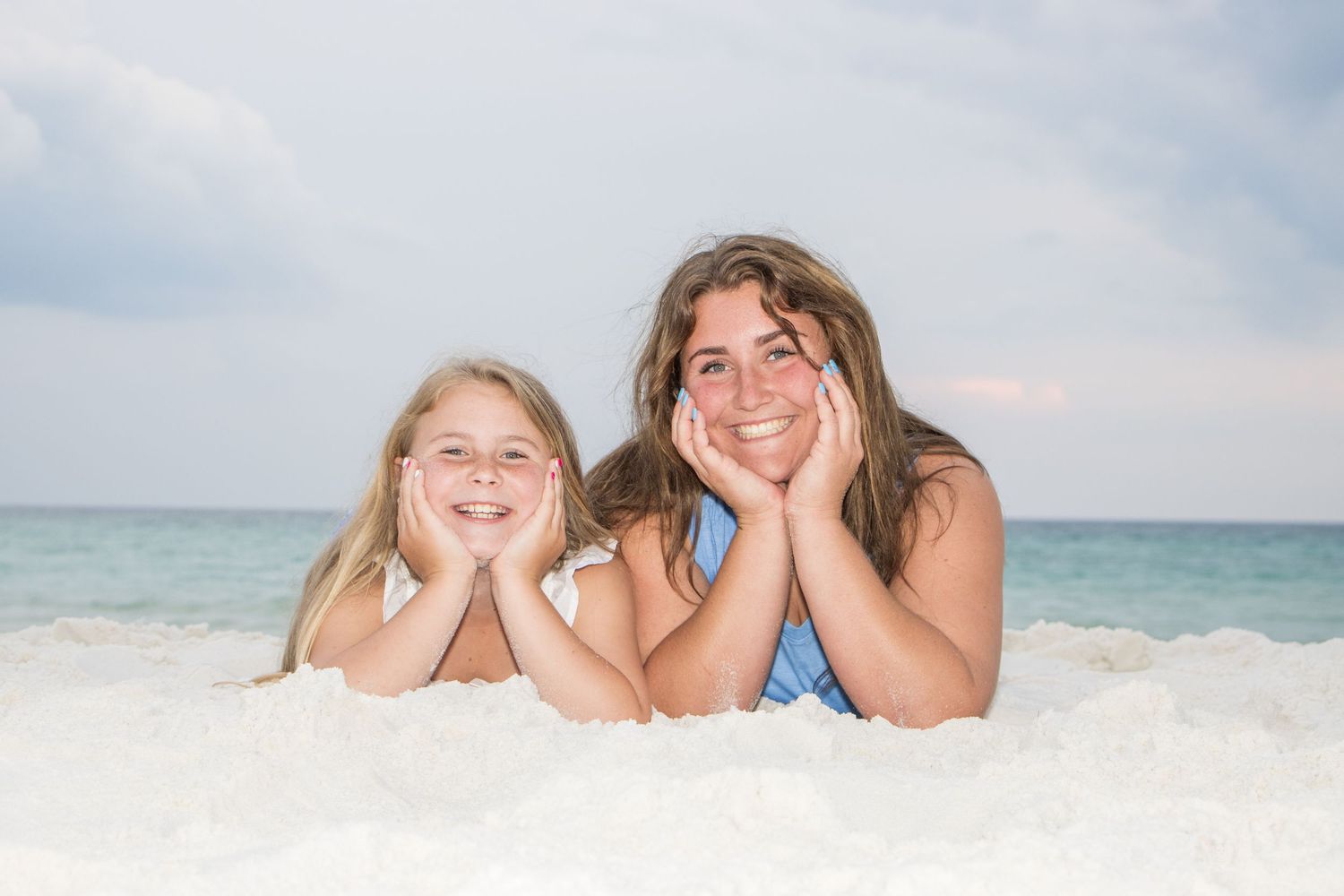 Candid beach photography of people lying in the sand with ocean waves in background.