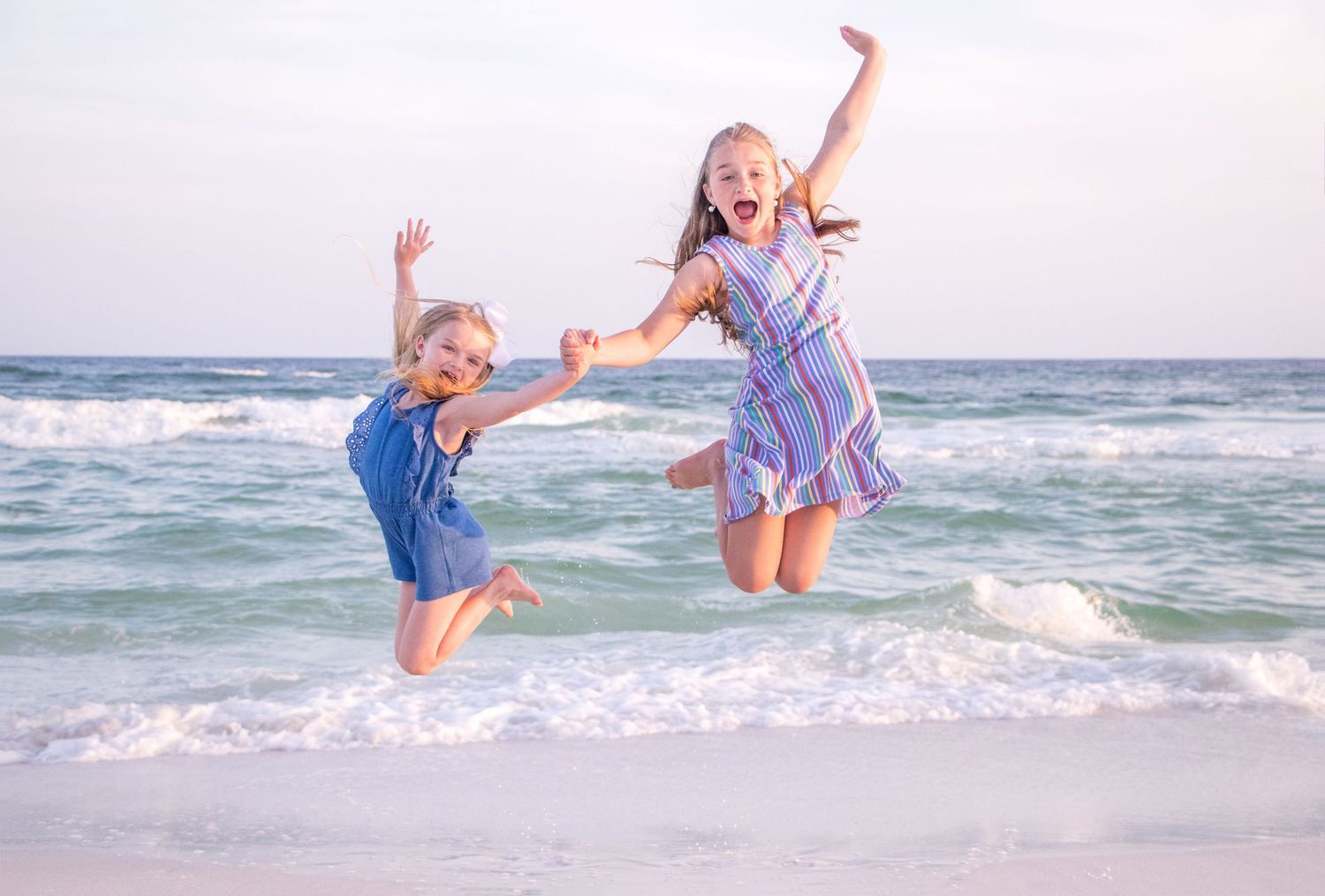 Playful beach photoshoot with joyful jumping and splashing in the ocean waves at sunset.