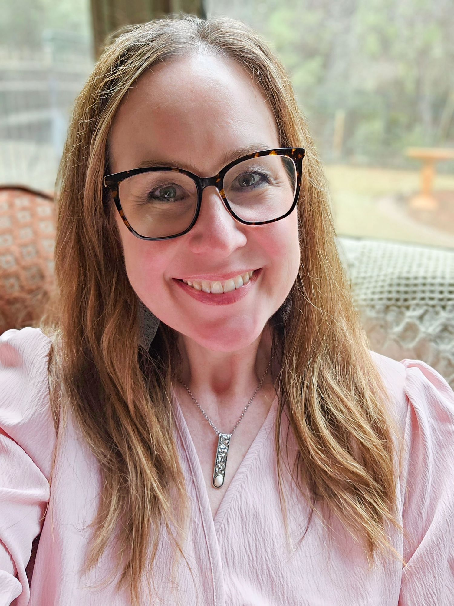 A series of four selfies showing Jolie with glasses and long brown hair wearing a pink top smiling at the camera.