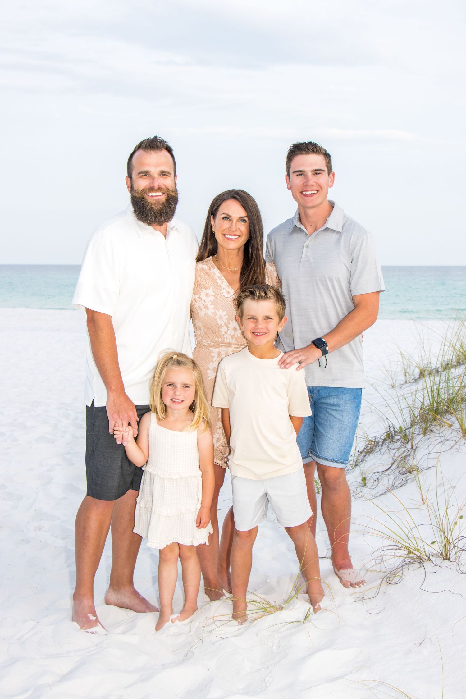 Family group photo session on coastal sand dunes with ocean view.