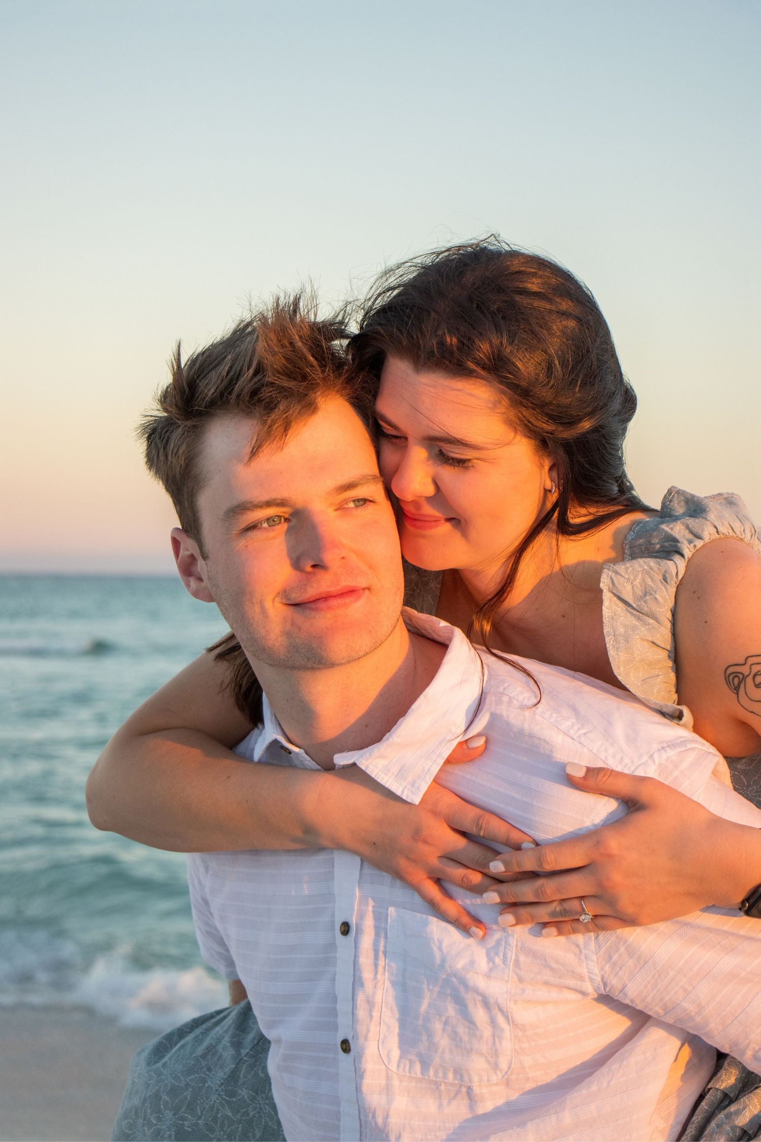 Couple sharing romantic embraces during sunset beach photography session.
