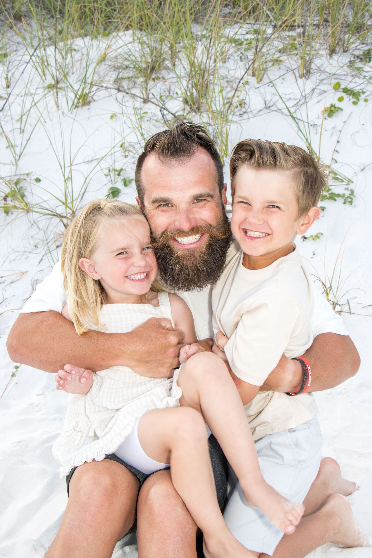 Intimate family portraits on white sand dunes with sea grass in background.