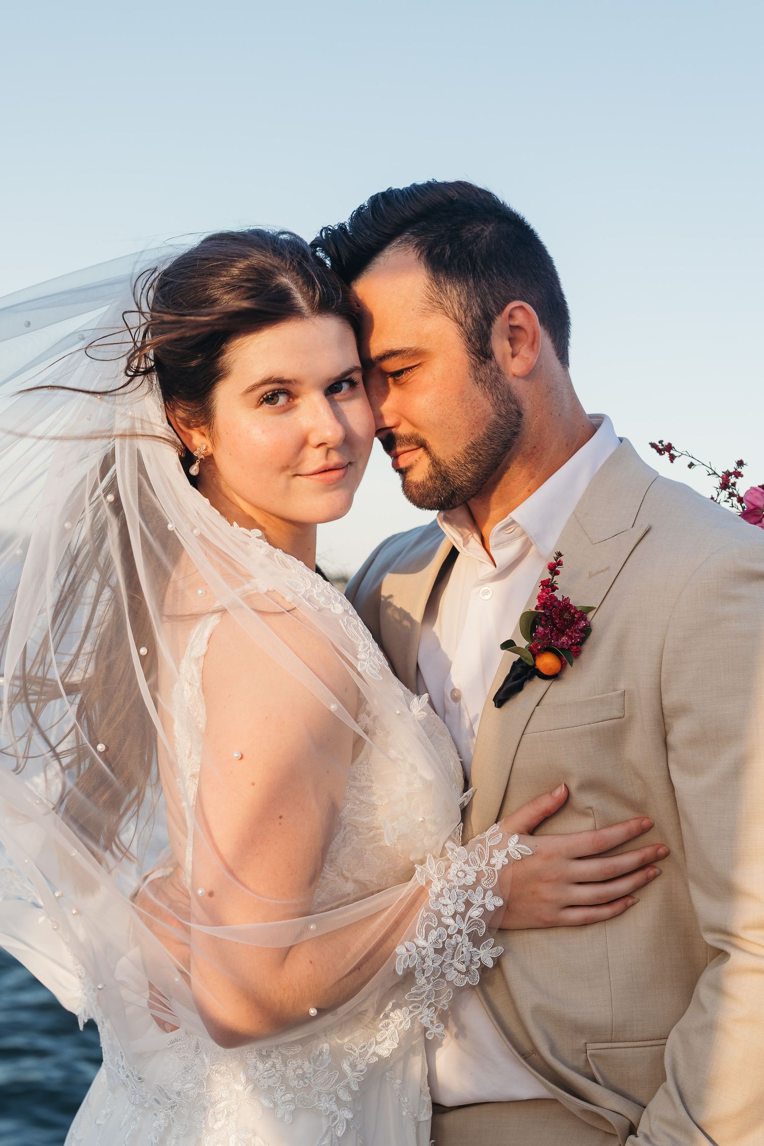 Romantic waterfront portrait with flowing veil and soft natural lighting.