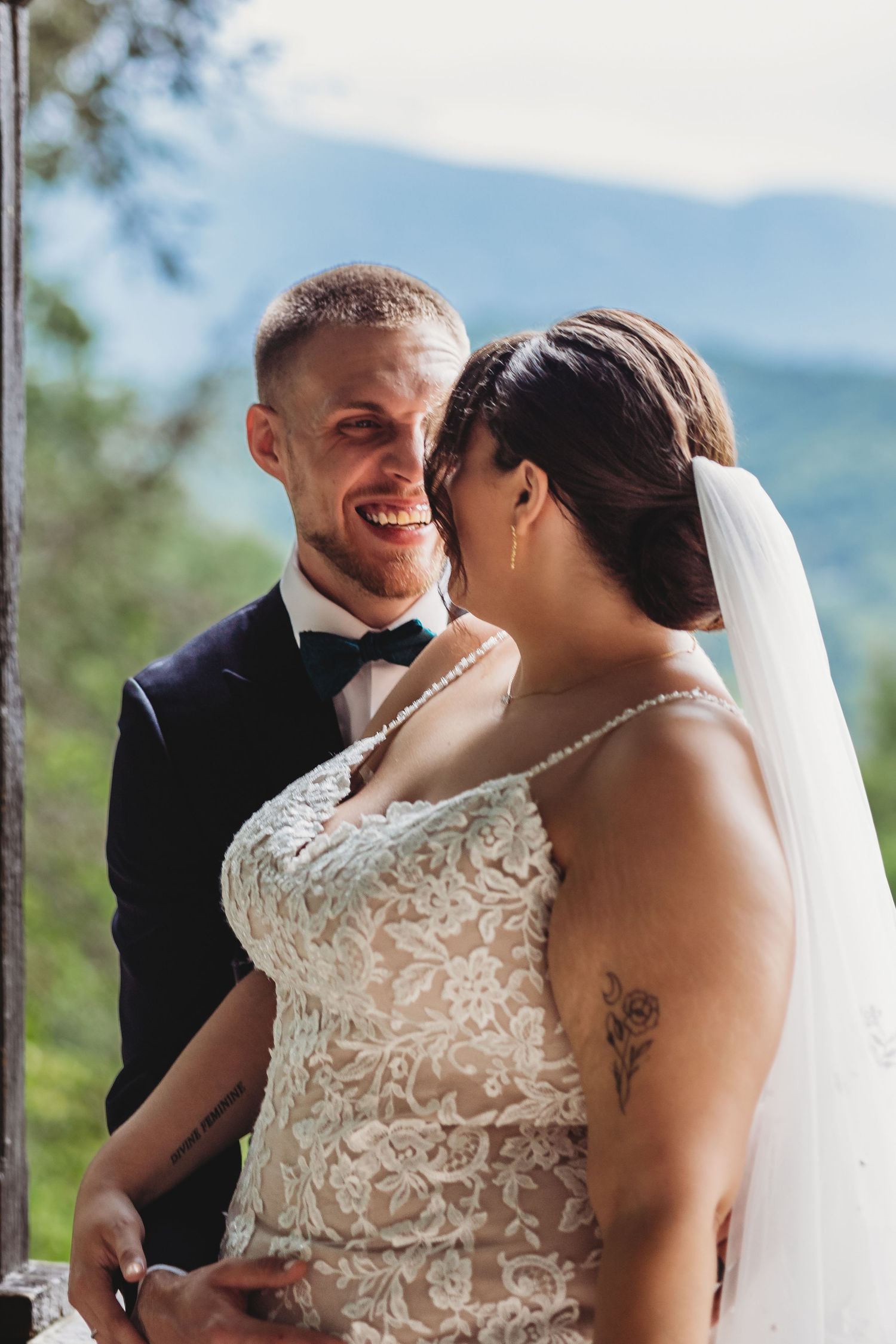 A bride and groom share a tender moment during their outdoor mountain wedding ceremony.