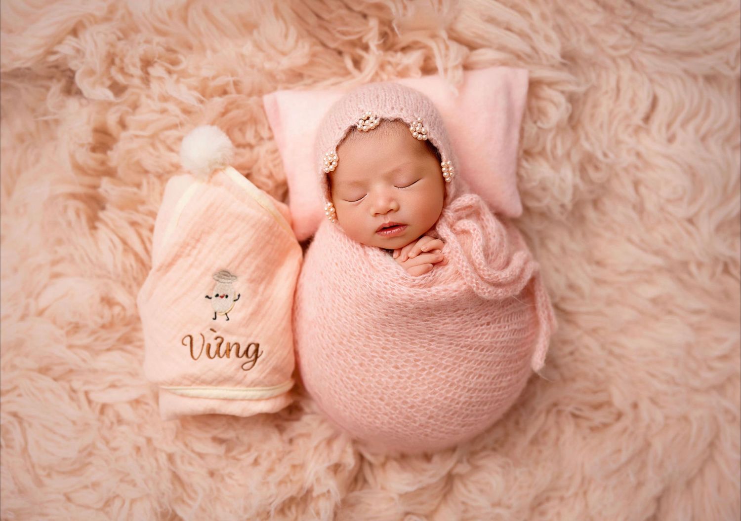 Newborn baby girl gently posed and wrapped in pink color in studio session