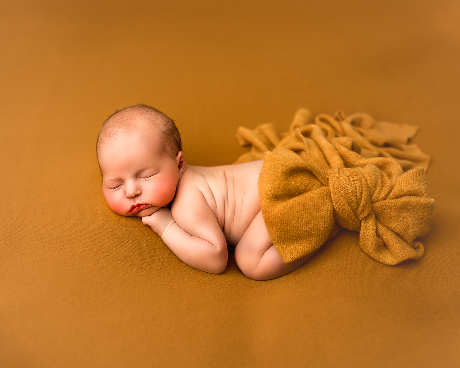 Artistic newborn photography on an orange backdrop showing peaceful sleeping poses.