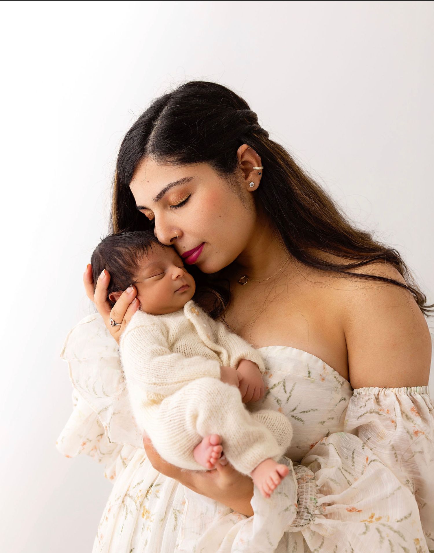 A tender moment captured in neutral newborn photography session as a mommy cradles baby