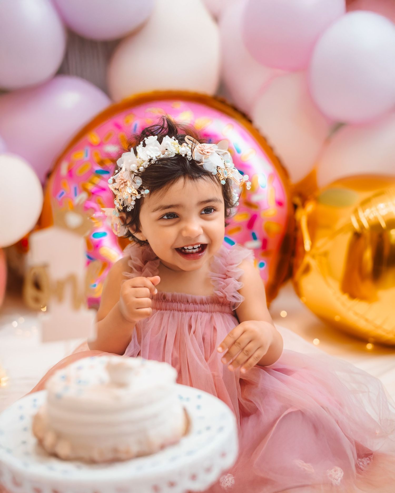 A party scene with pink balloons, a donut-shaped decoration, and a birthday cake against a pastel background at seattle milestone photograph