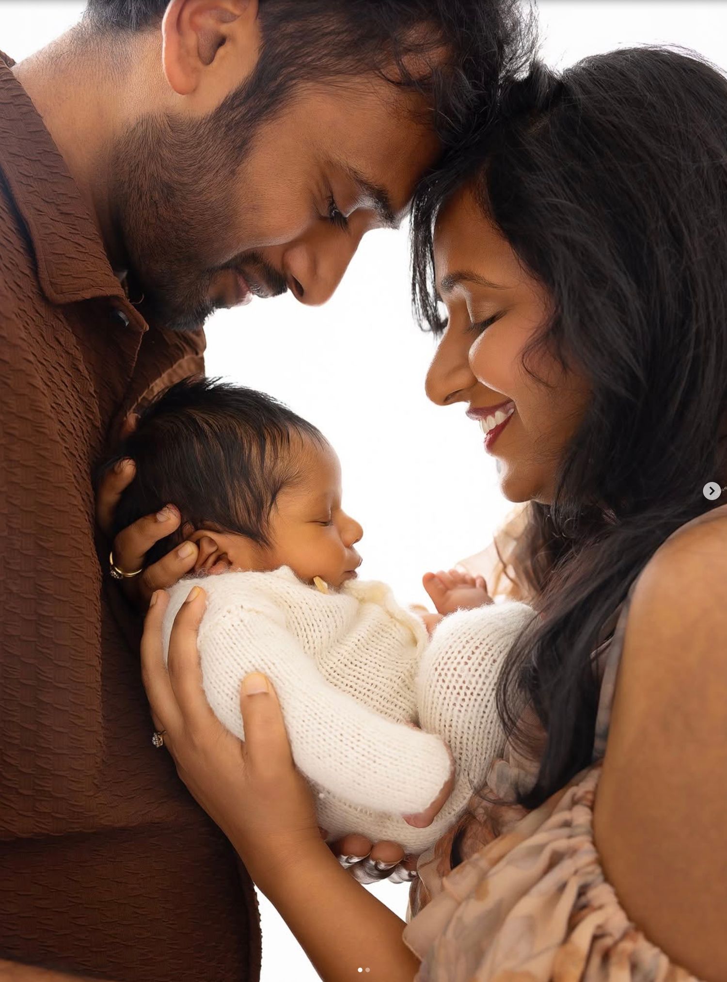 A tender parenting moment shows gentle interaction with a small baby wearing a white outfit.