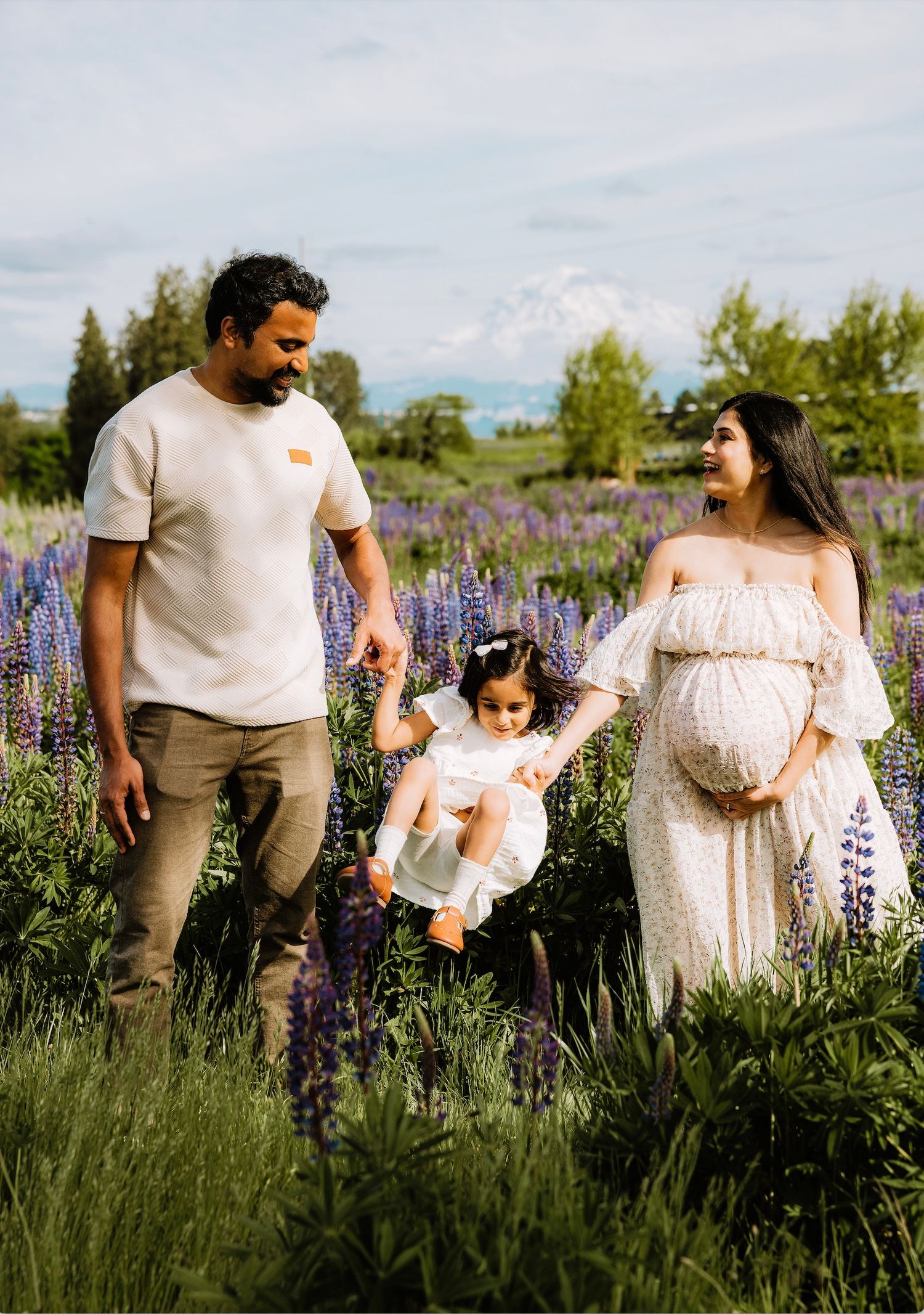 Family enjoying a sunny day together in a field of purple lupine flowers during a spring outdoor photoshoot.