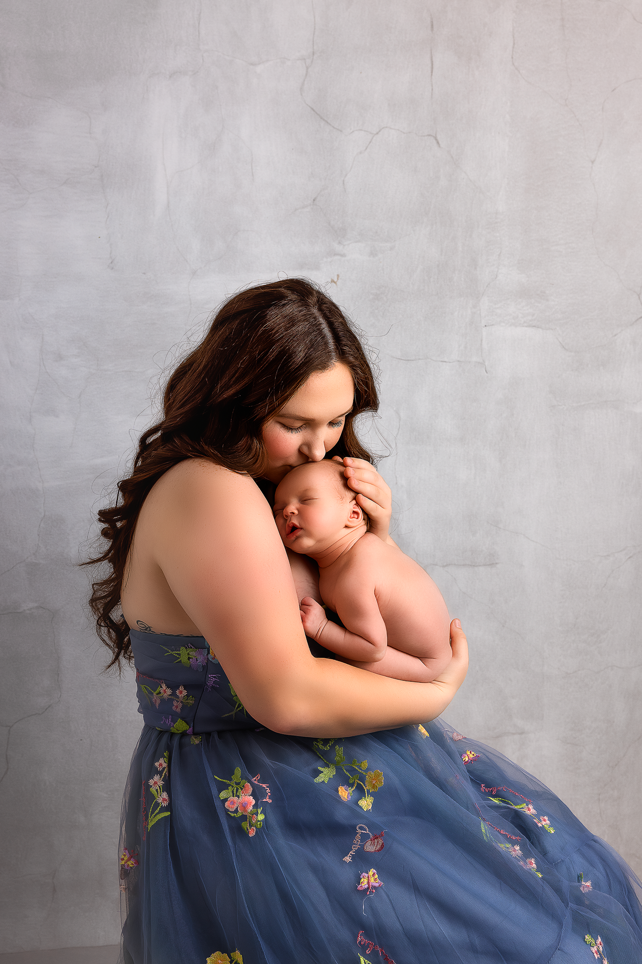 A tender moment captured in a series of artistic portraits showing gentle embraces against a gray backdrop.