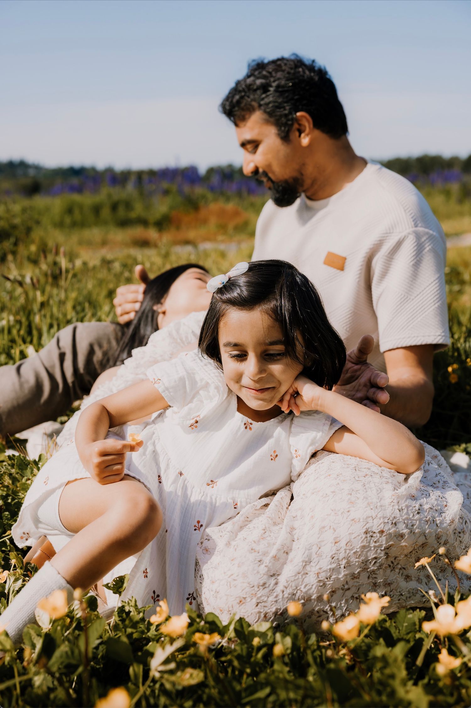 A couple relaxes together in a sunny meadow filled with wildflowers on a warm afternoon.