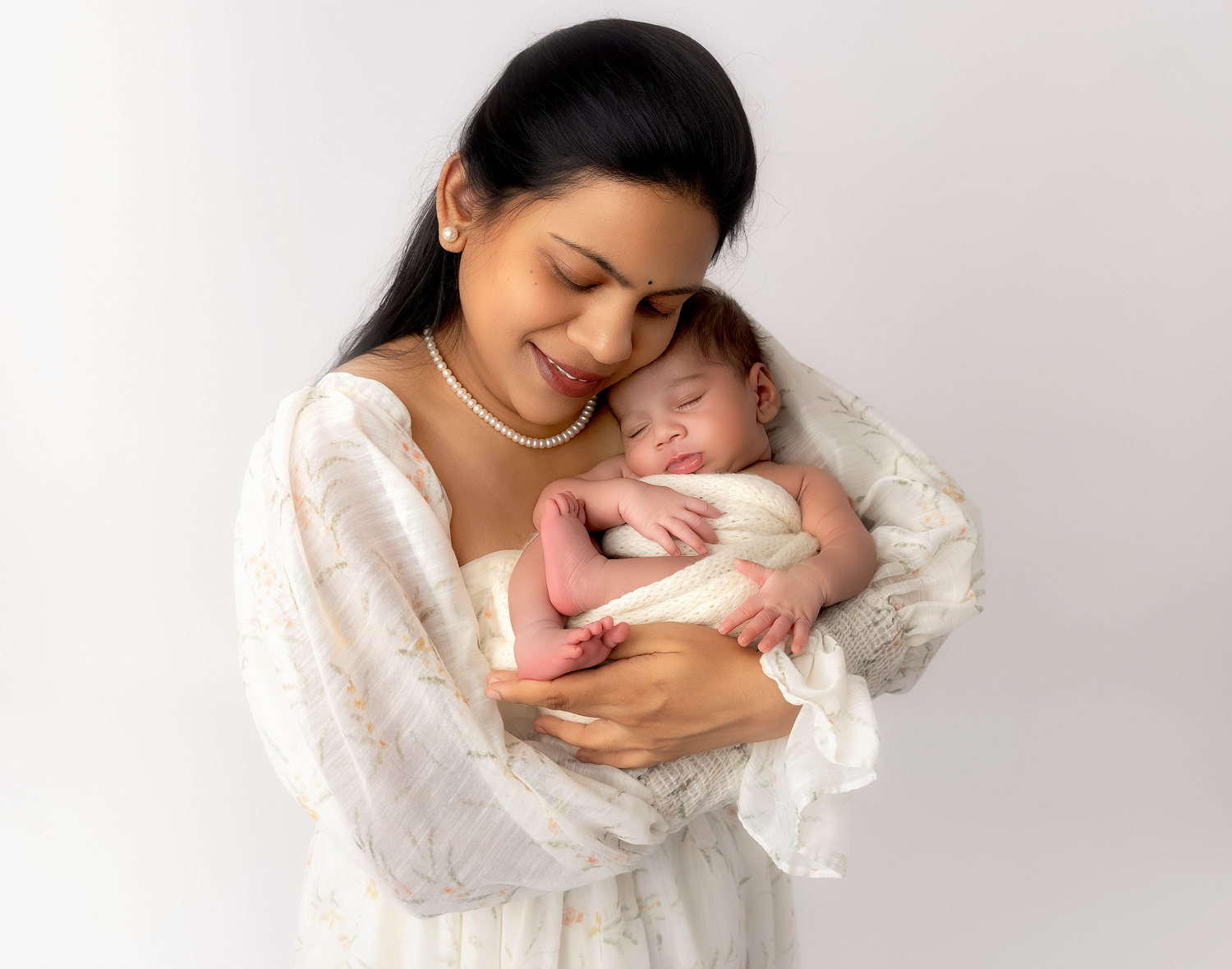 mommy holding newborn baby as they embrace in soft white clothing against a light background.