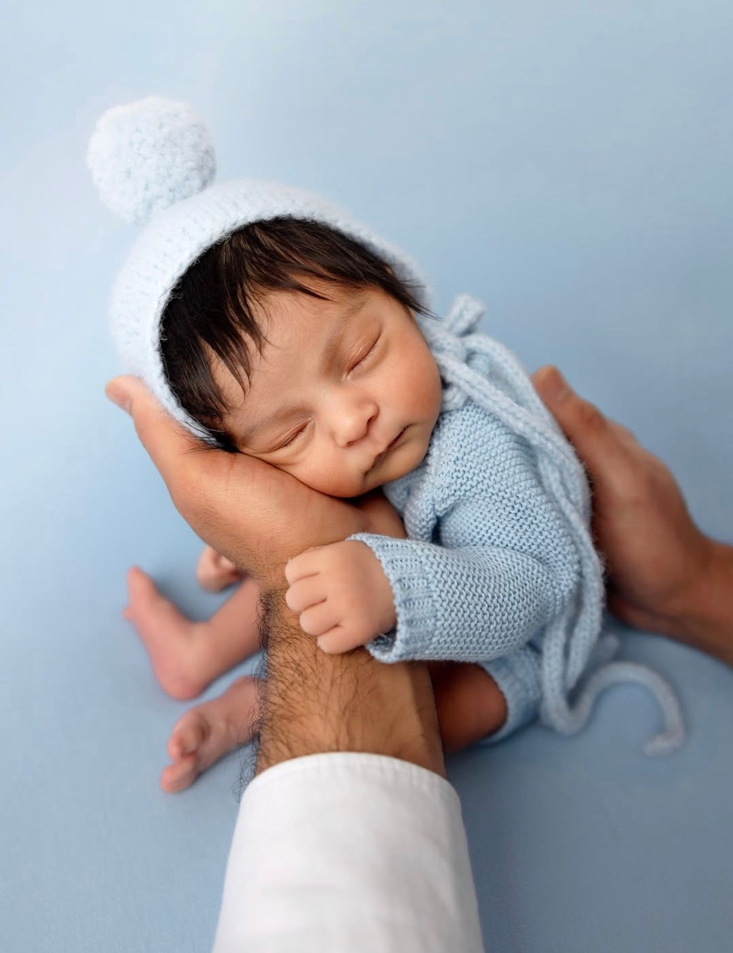 Newborn baby portrait captured in soft light styled in blue sweater studio setup