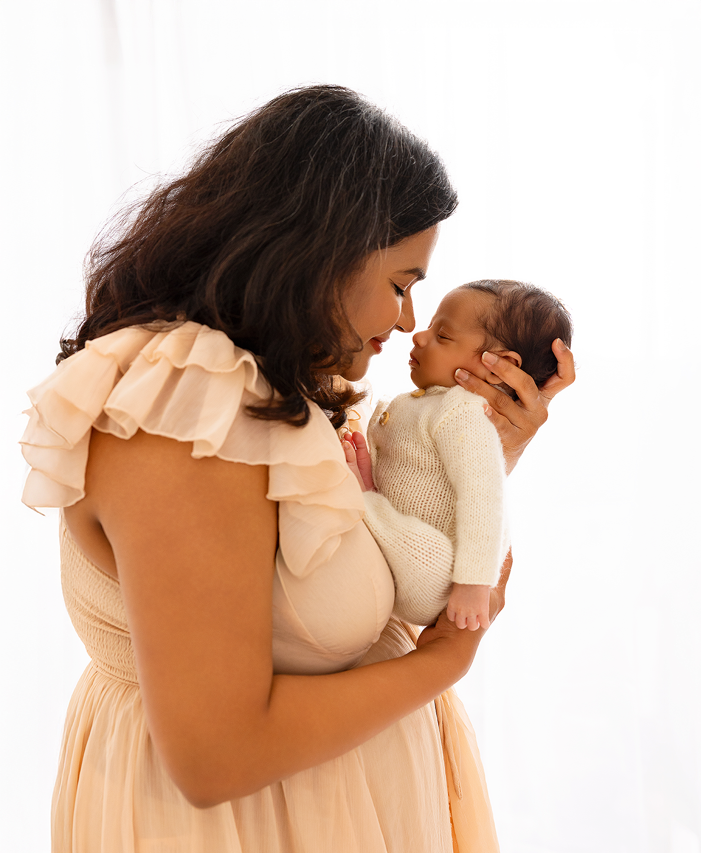 A series of photos showing a tender embrace between parent and child in white clothing against a light background.