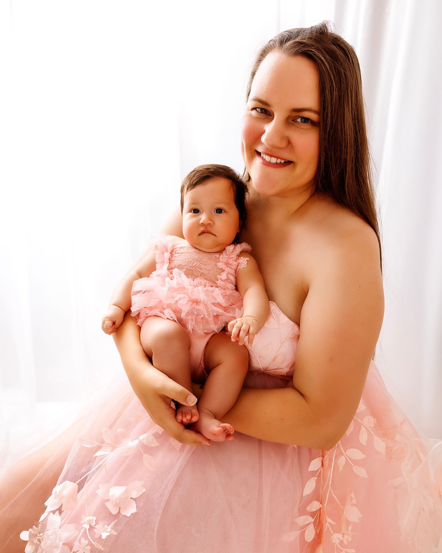Parent and baby in matching pink tulle dresses pose for portrait.