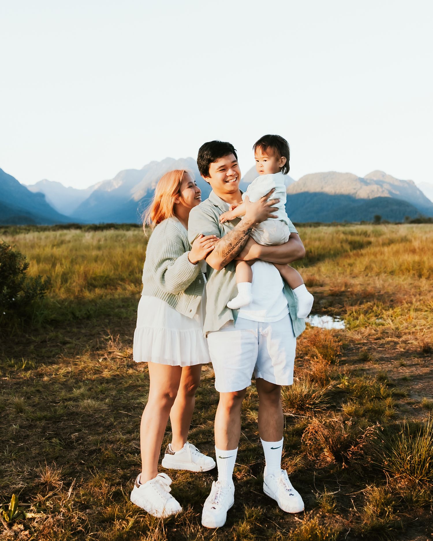Family shares tender moments together against backdrop of majestic mountains during golden hour photoshoot.