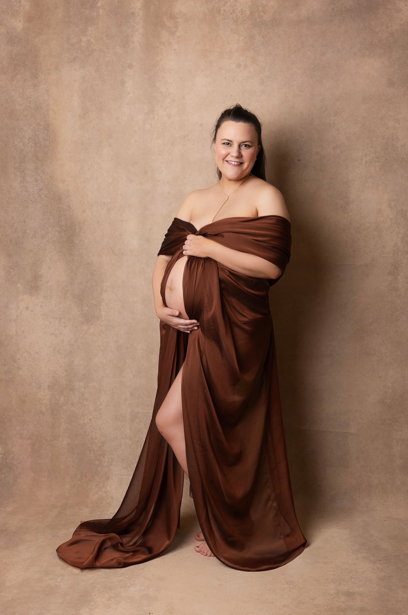 Artistic portrait series showing a person wrapped in brown fabric against a textured beige backdrop in various poses.