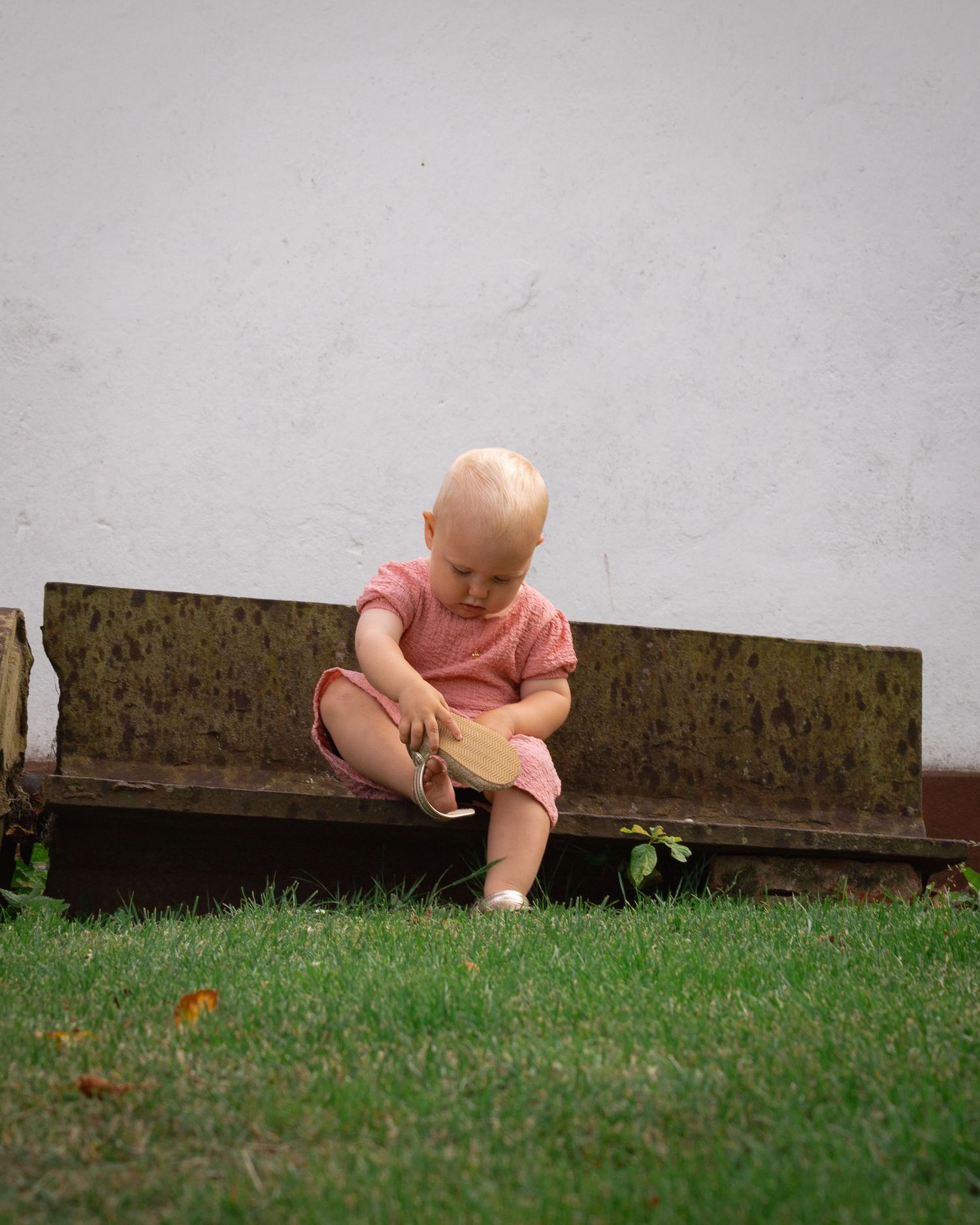 En liten flicka sitter och försöker fixa till skon.