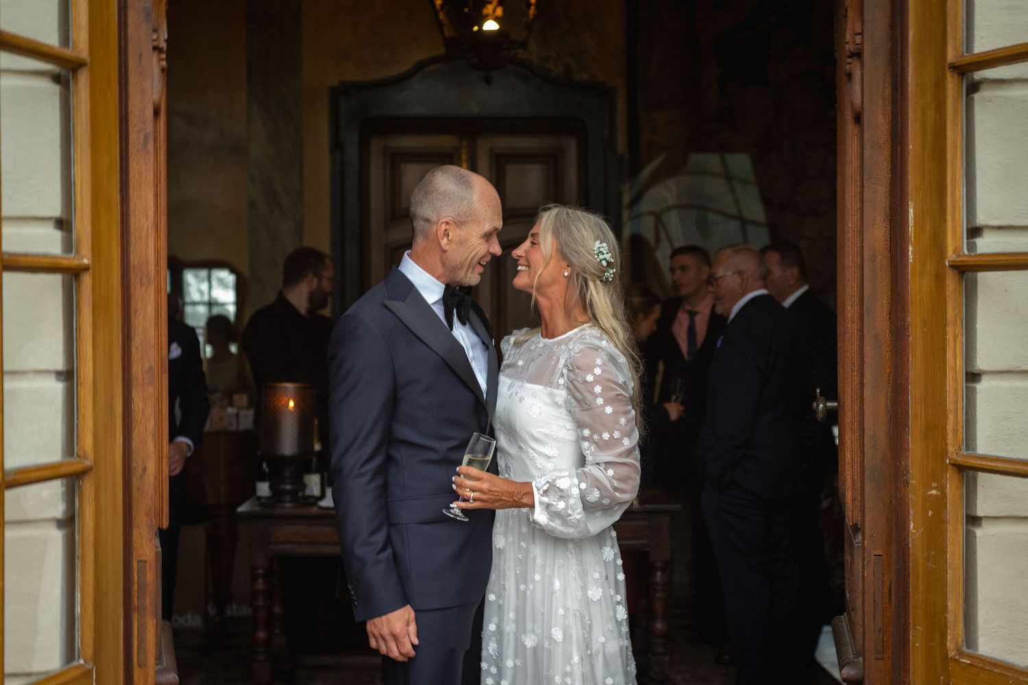 I en dörröppning står ett brudpar och ler mot varandra.