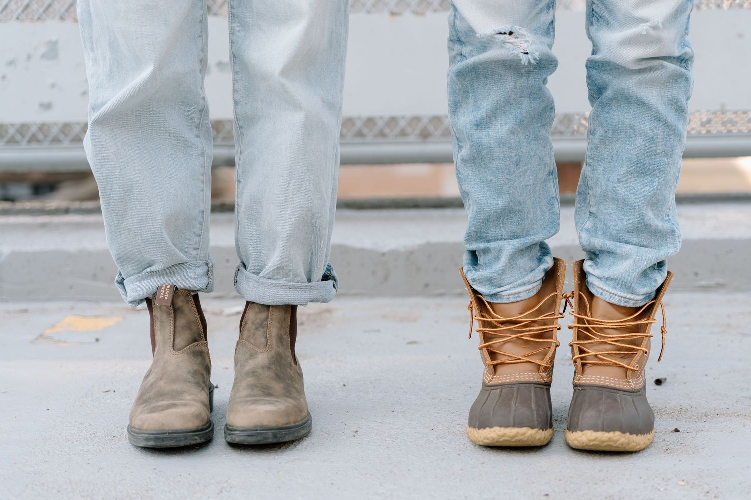 Close-up of matching boots and jeans standing on concrete.