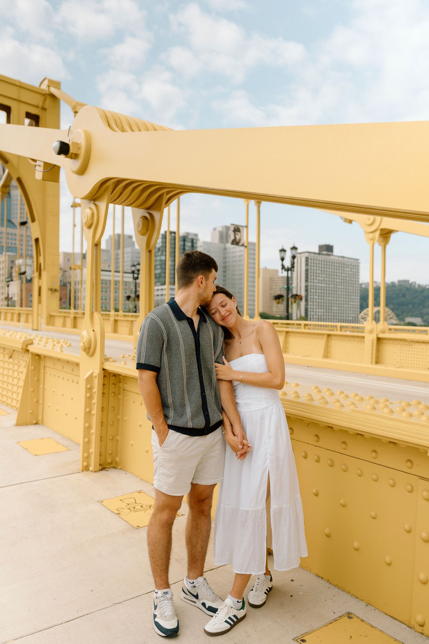 A couple in wedding attire shares an intimate moment on a yellow painted bridge in Pittsburgh, PA