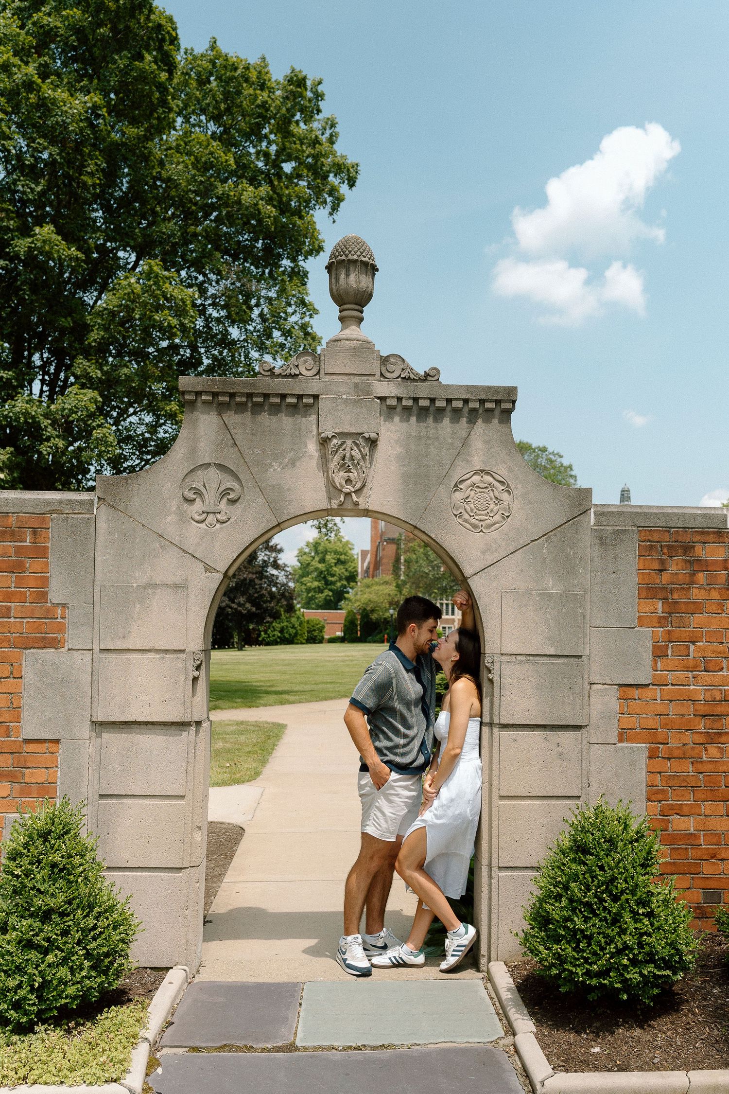 Progression sequence showing stone gateway pillars and entrance with decorative architectural details and bushes beside brick walls.