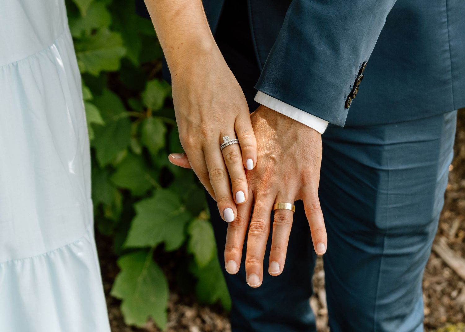 Close-up detail of hands and clothing as couple walks together outdoors.