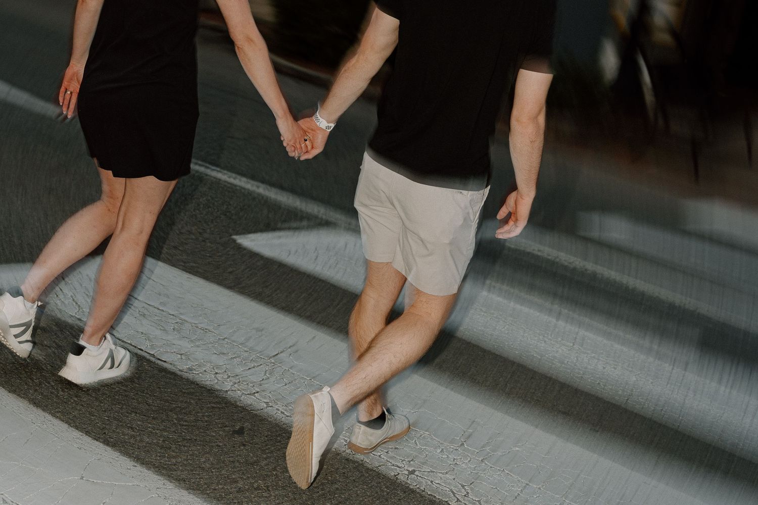 A series of casual shoes and legs walking on a concrete surface.