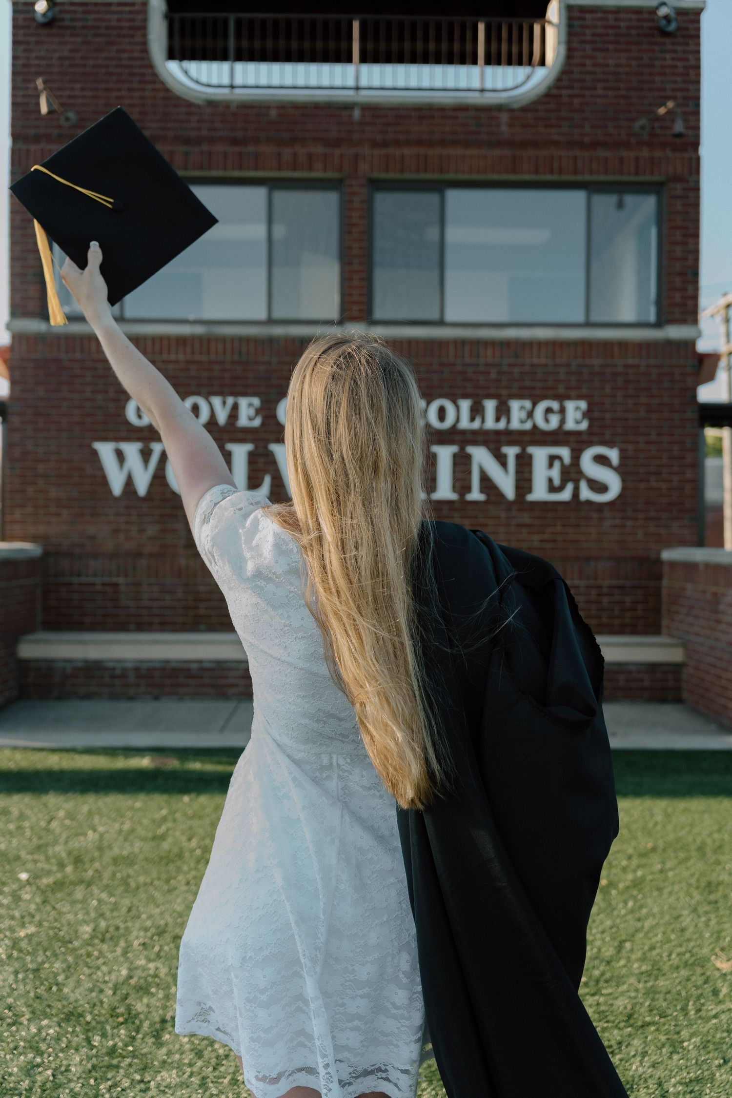 Group of graduates toss their caps in the air while celebrating outside a brick building.