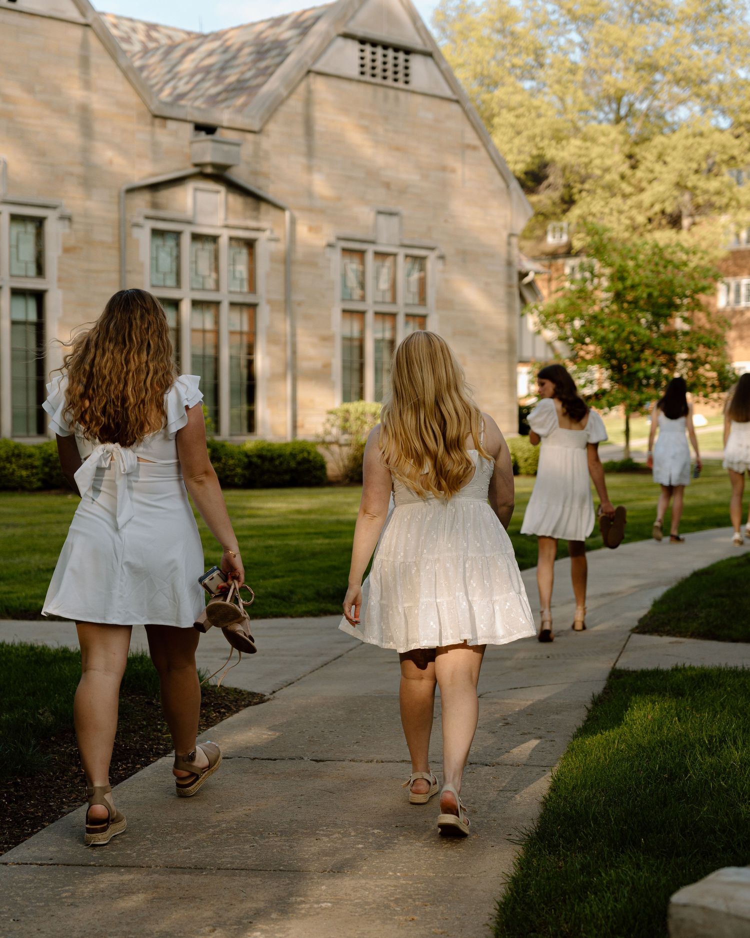 Group walking together on a sidewalk near stone buildings on a college campus.