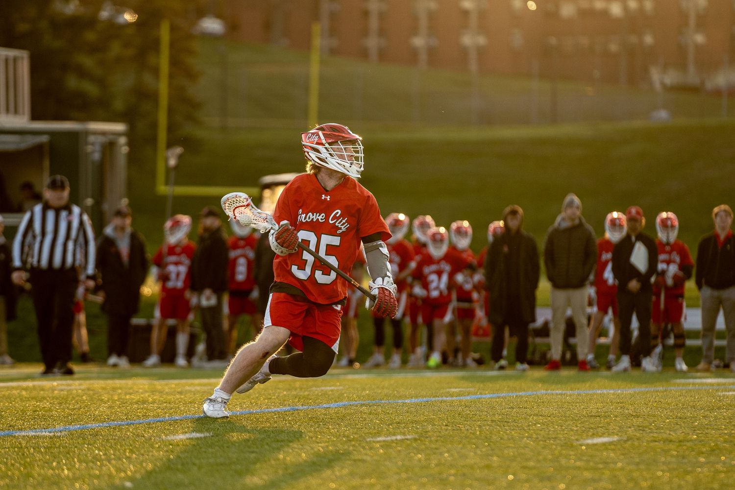 Football players in red jerseys practicing on sunny field.