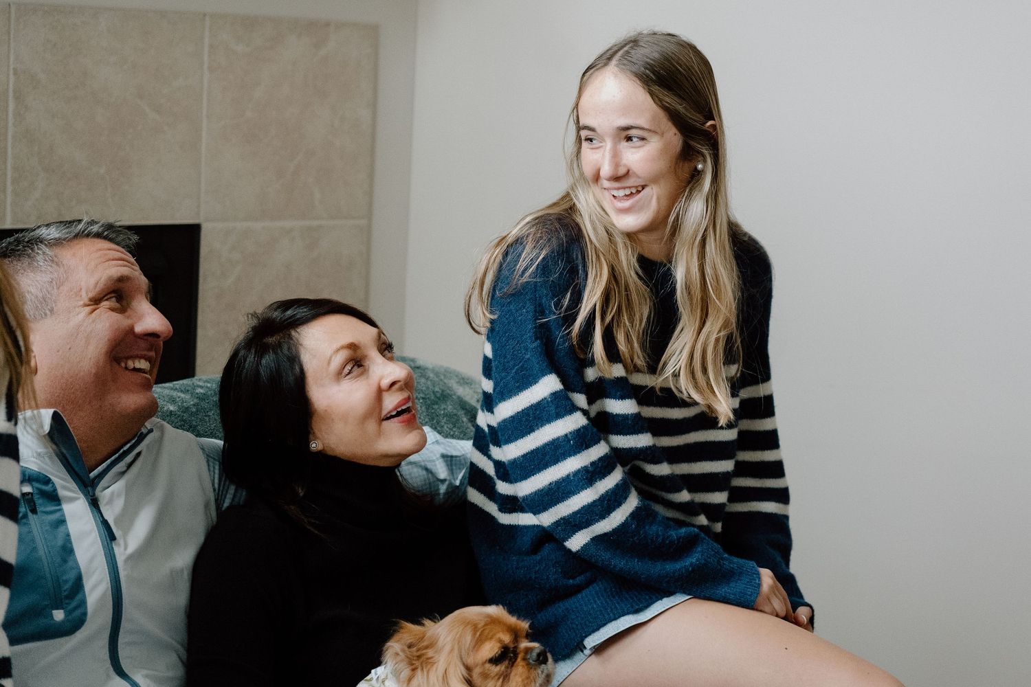 Couple posing for candid shots with genuine laughter and smiles in a casual indoor setting.
