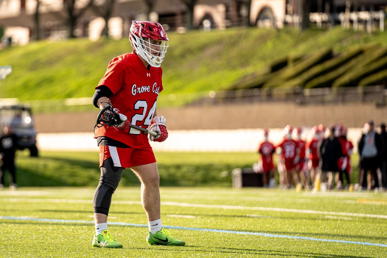 Athletes in red uniforms playing on sports field during golden hour.