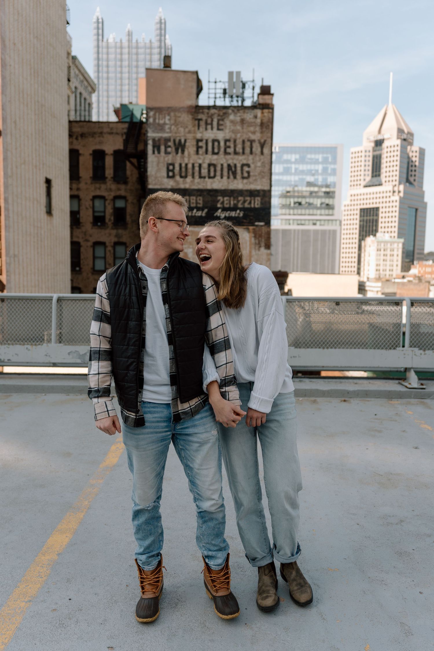 A couple enjoying a moment together on an urban rooftop with city buildings in the background.