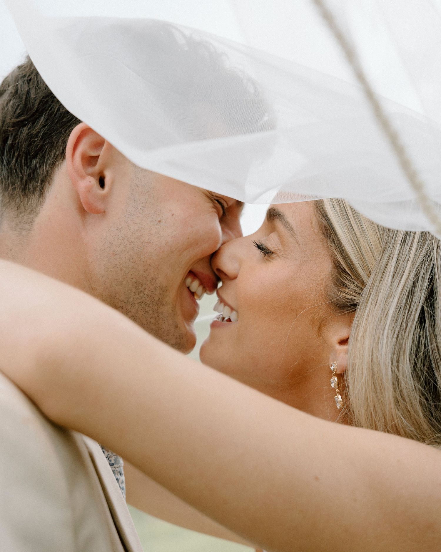 Intimate close-up of bride and groom sharing tender moment under veil.
