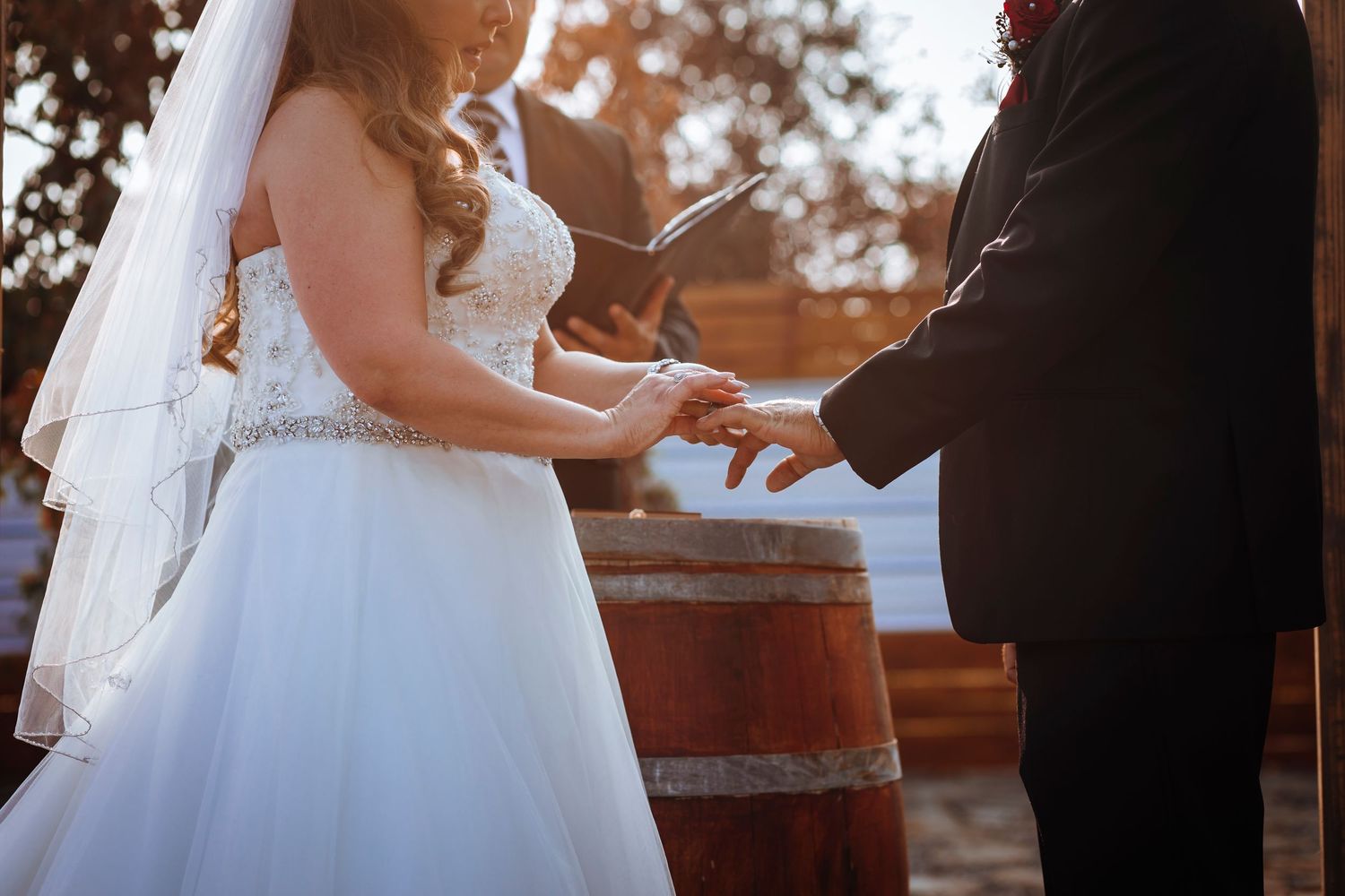 Close-up of couple exchanging rings during outdoor wedding ceremony.