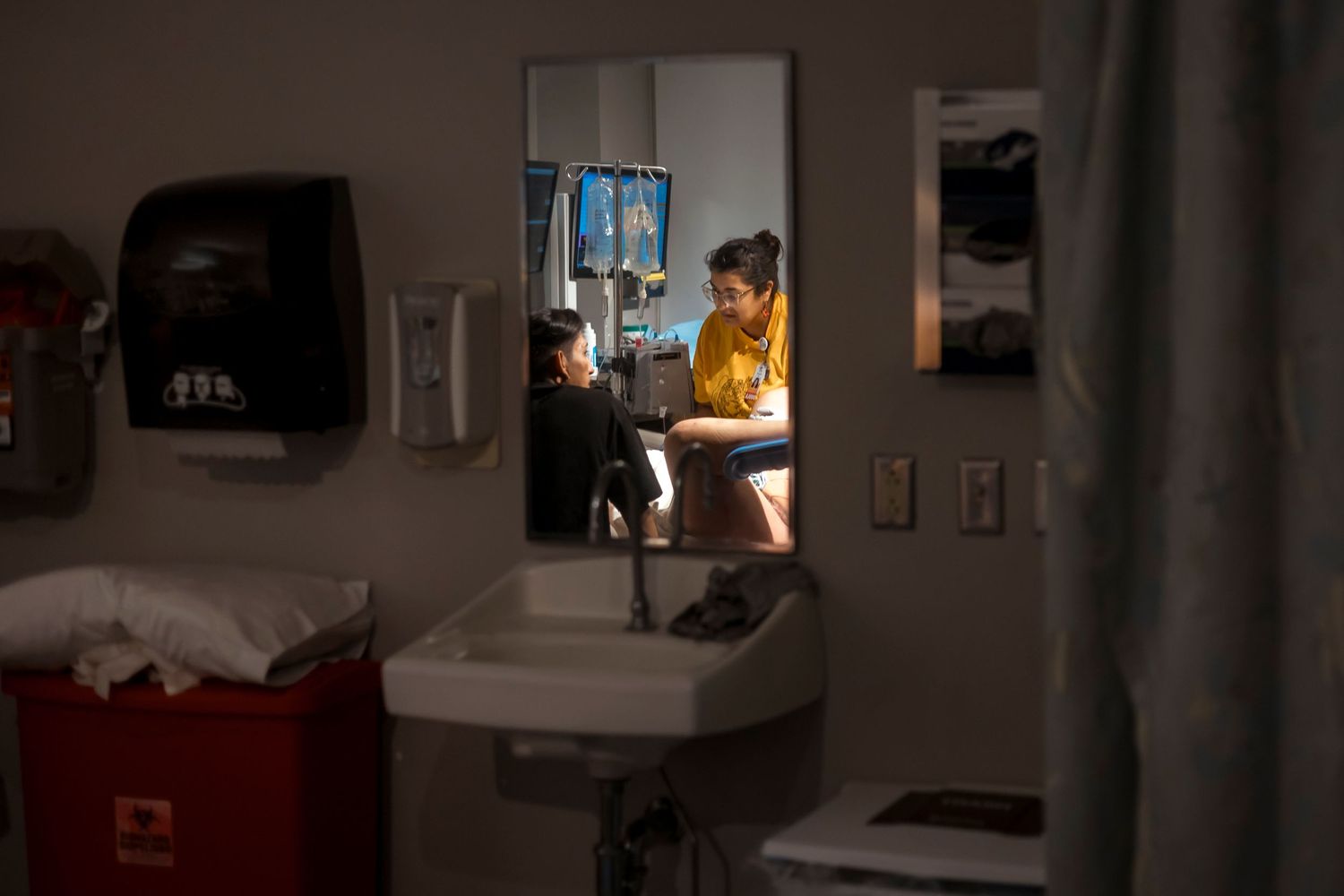 Hospital delivery room scene with medical equipment and dim lighting.