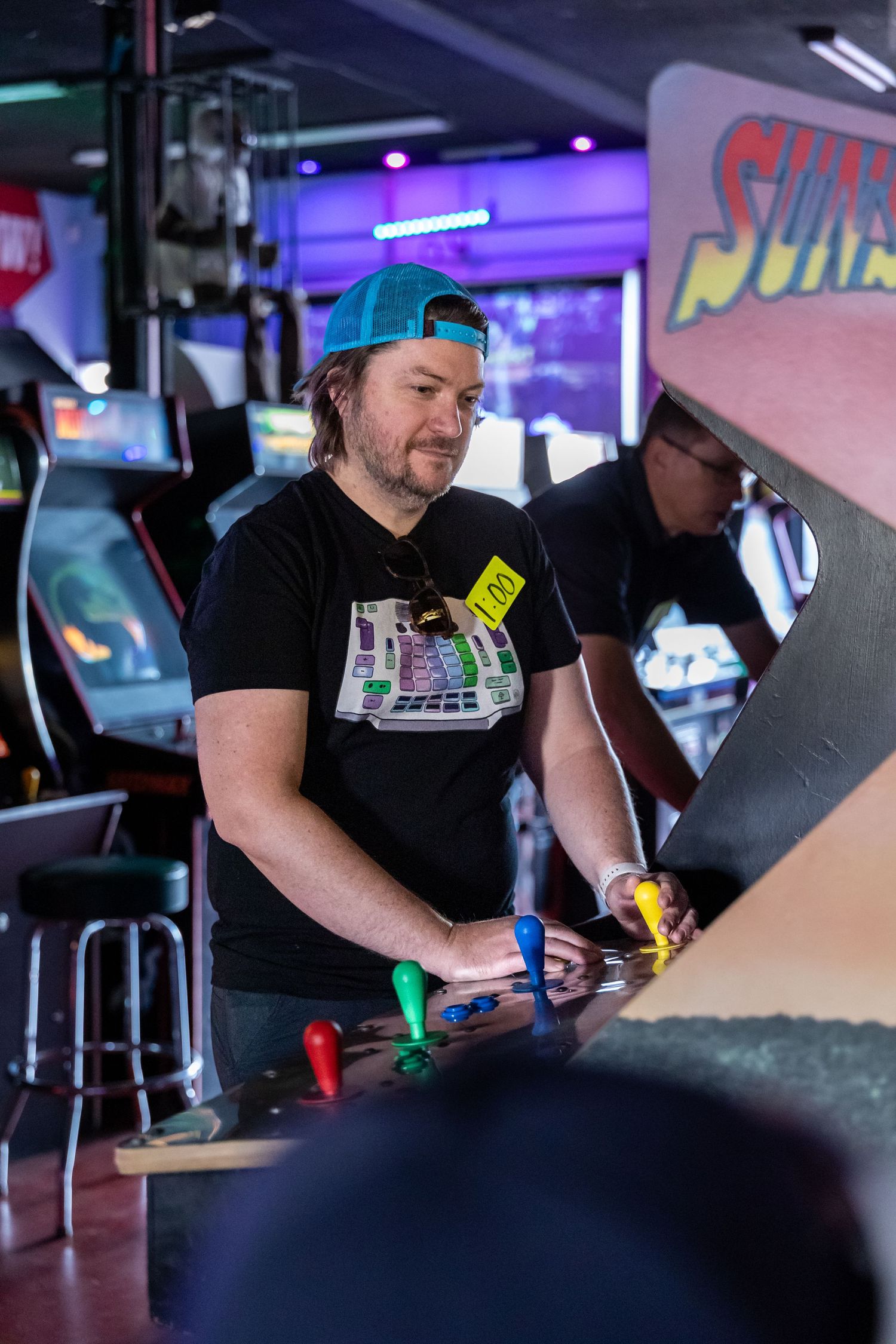 Players interact with arcade games in a dimly lit gaming venue.