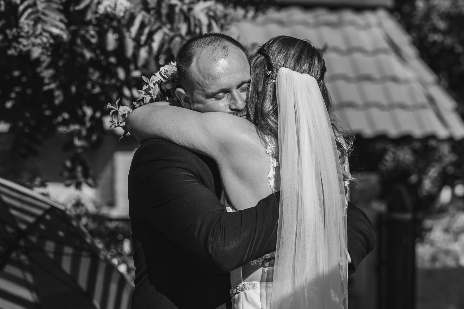 A tender embrace between newlyweds during their outdoor wedding ceremony in Redlands, captured in black and white photography.