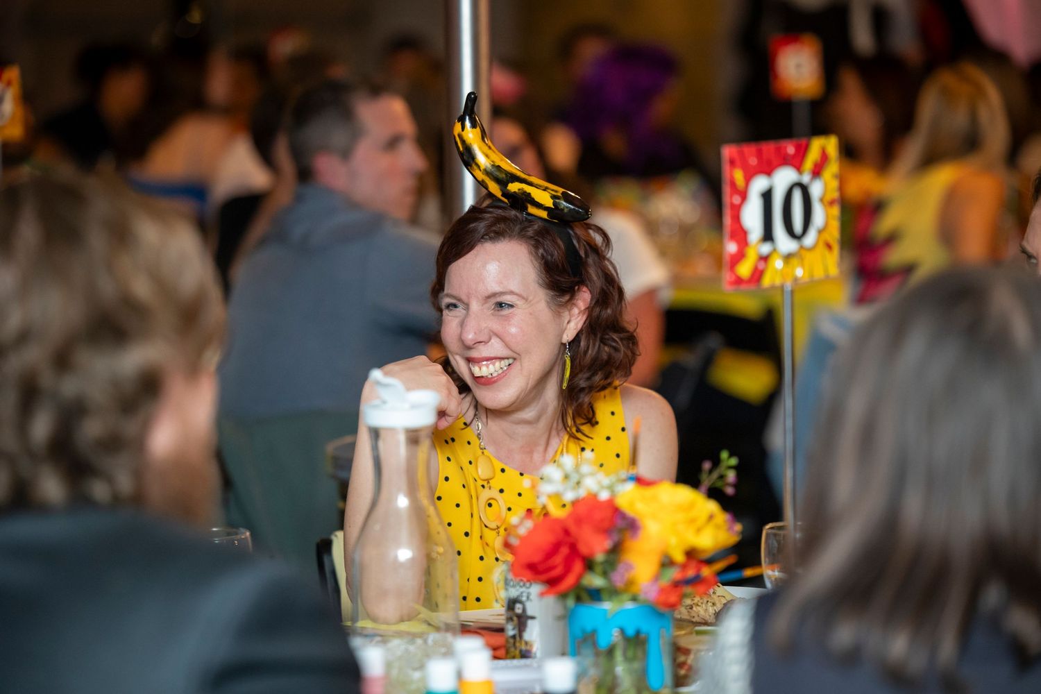 Guests seated at round tables during an evening event with colorful decor.