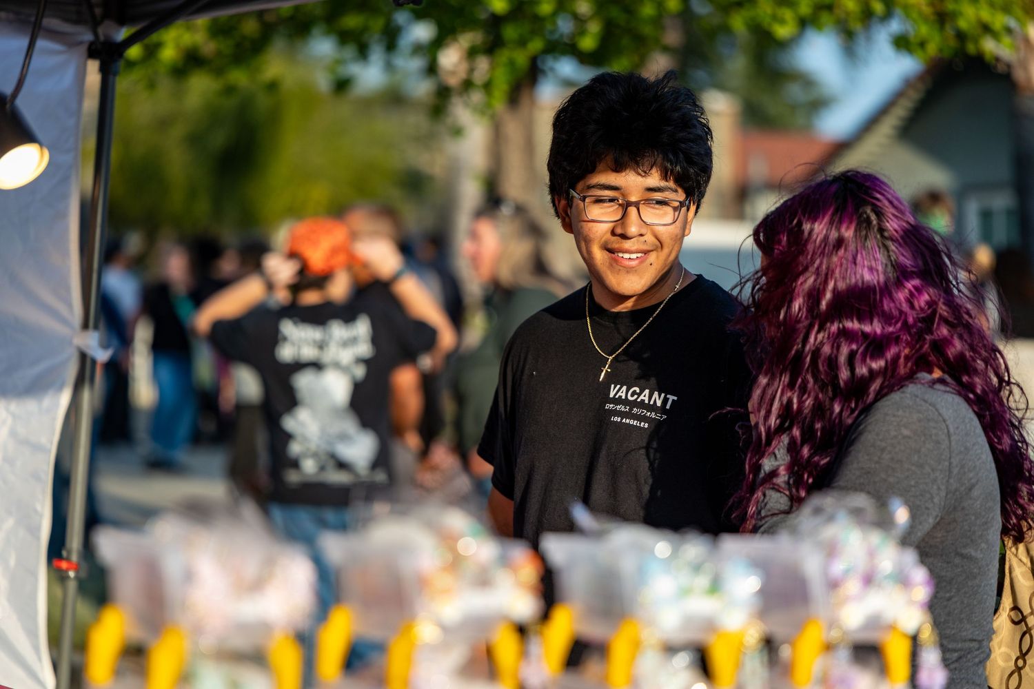 Vendor stands at an outdoor market booth with colorful merchandise on display.