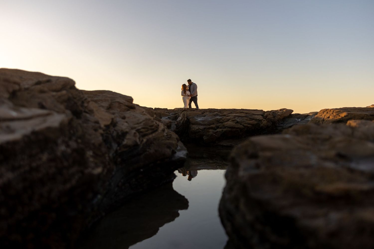 People watching a dramatic orange sunset from a scenic cliff edge overlooking the ocean at popular tourist spot in Huntington Beach.