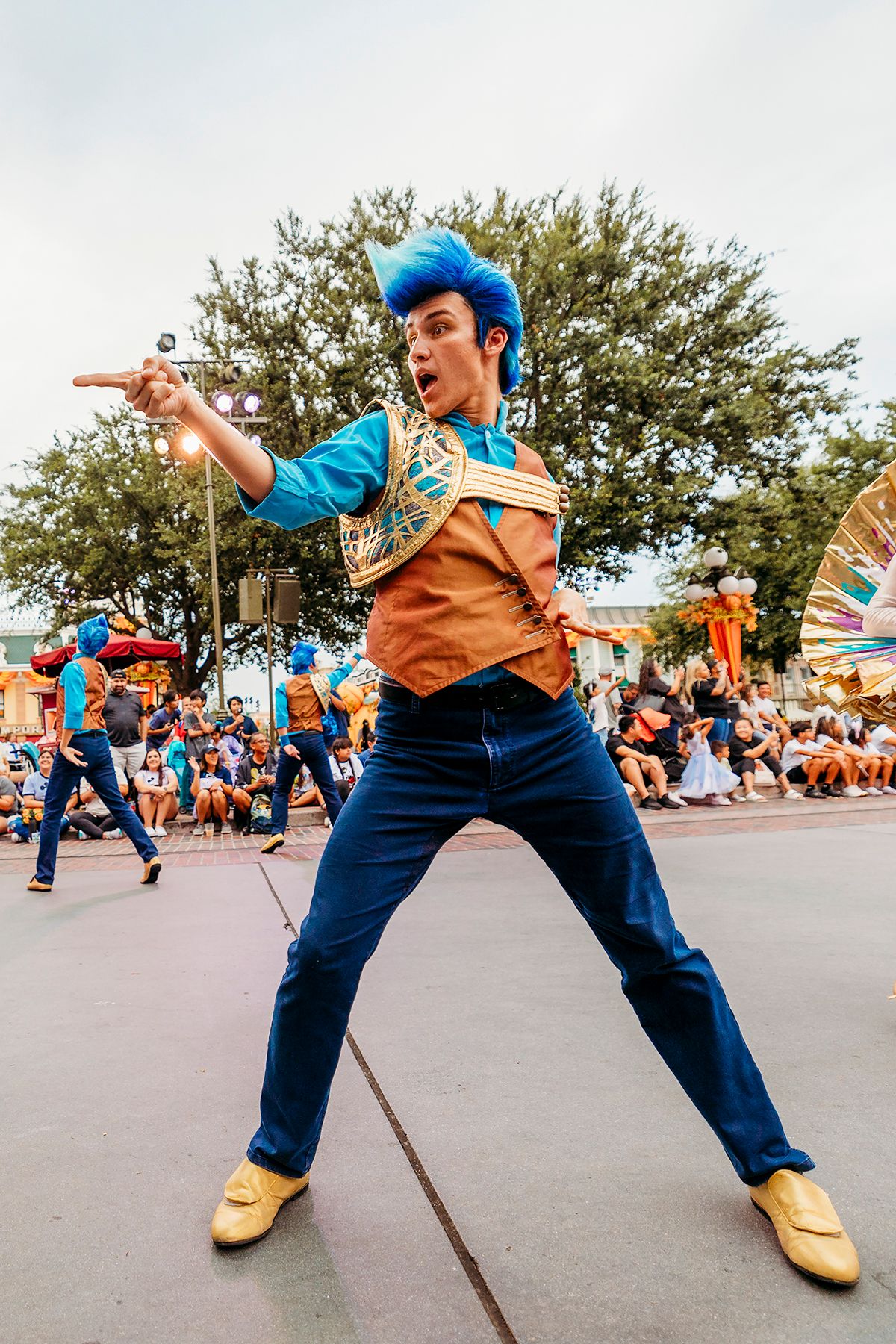 Street performer in blue costume striking dynamic poses during outdoor entertainment show.