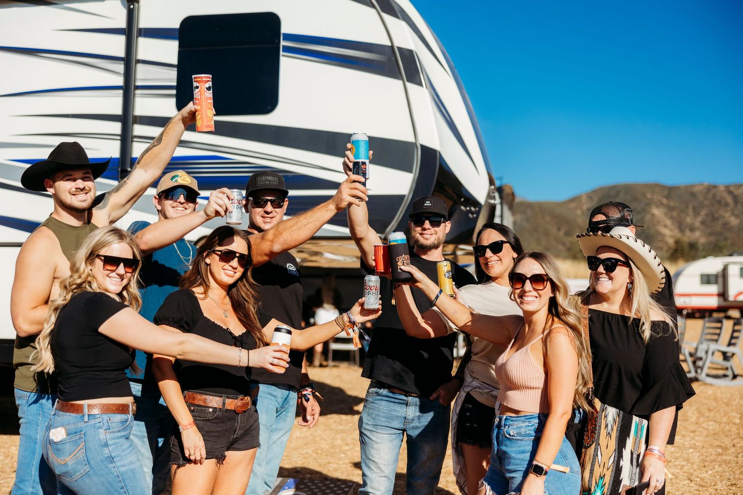 Festival attendees celebrating together outside an RV in the desert.