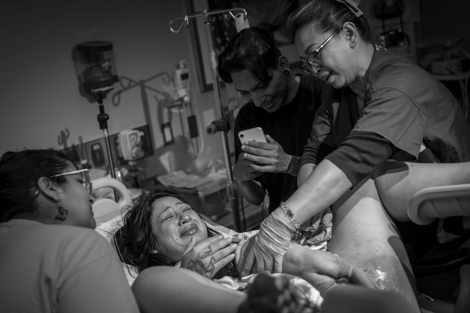 Hospital room filled with medical staff during intense delivery moment.