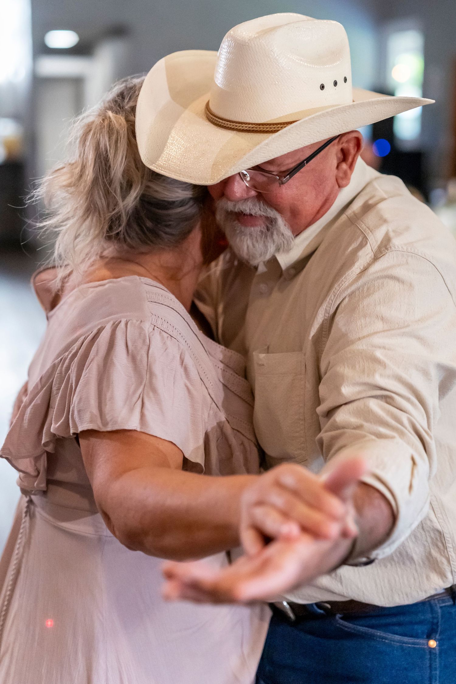 Country western dance moment with cowboy hat at wedding reception.