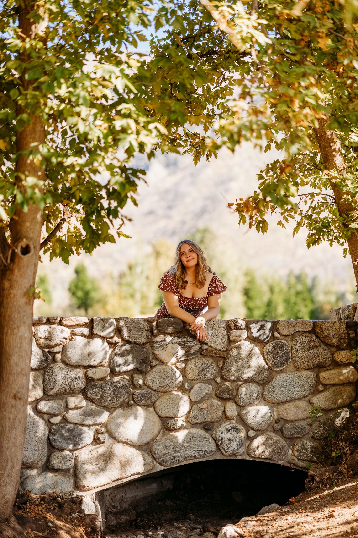 A rustic stone bridge surrounded by trees creates a charming outdoor setting in Redlands.