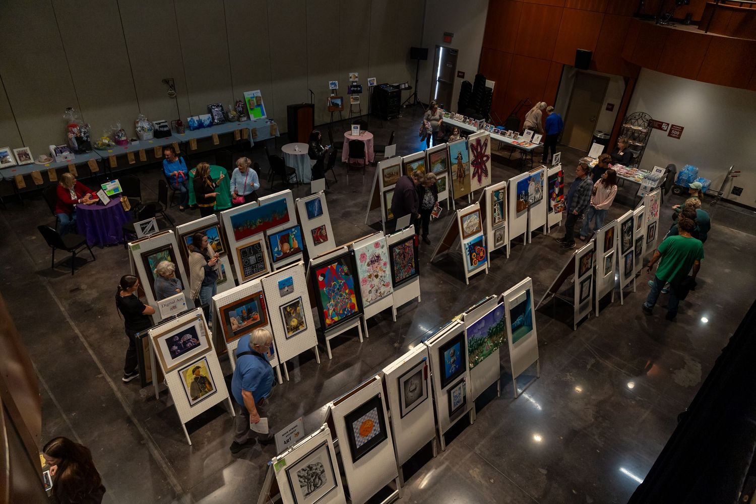 Art gallery exhibition displaying multiple framed photographs in organized rows on dark floor.