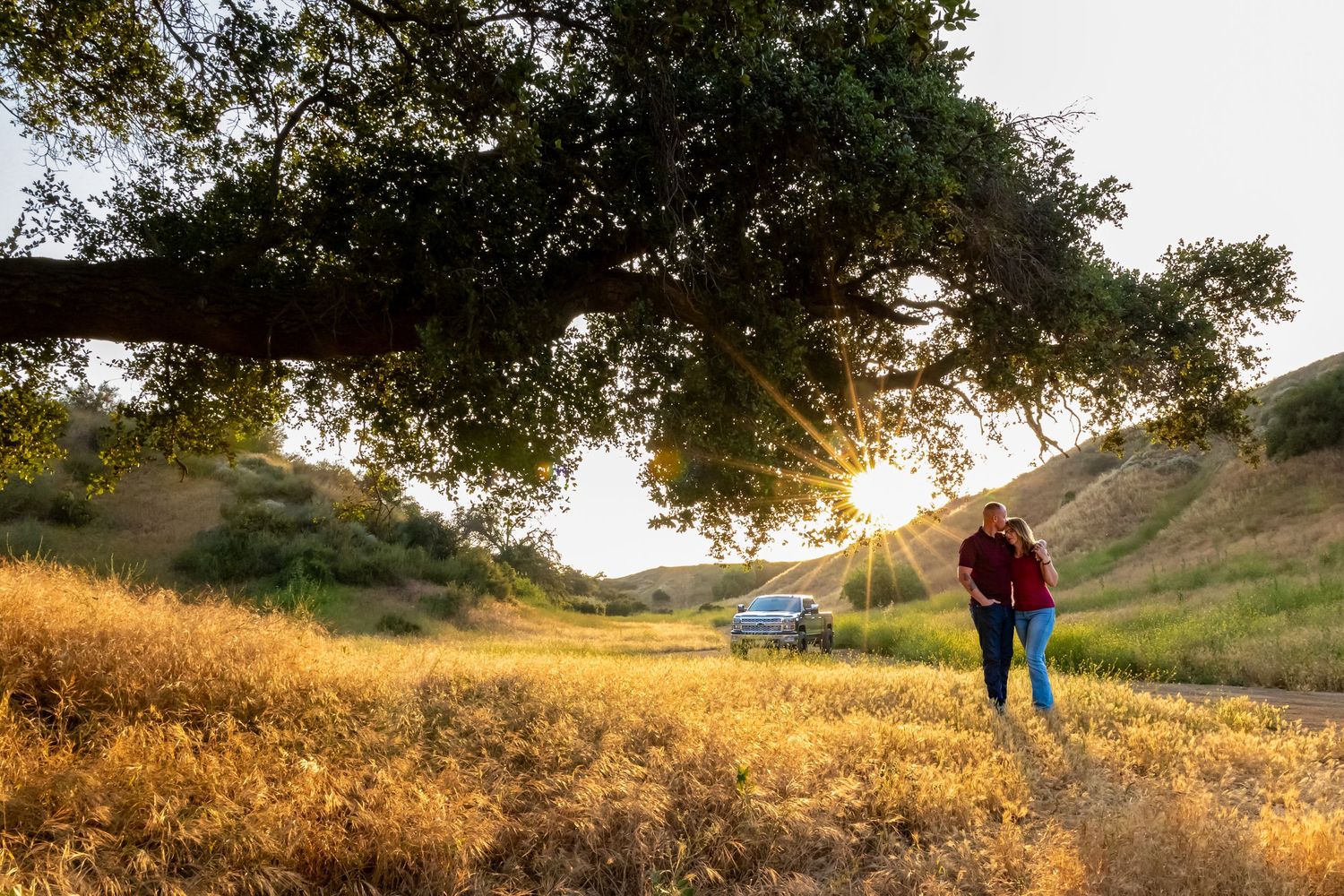 Two people share a moment in a sun-drenched field during golden hour.